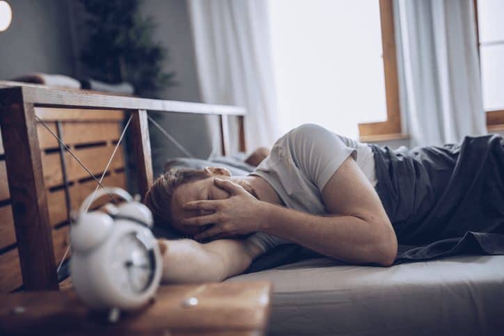 Sleeping Man Disturbed by Alarm Clock Early in the Morning
