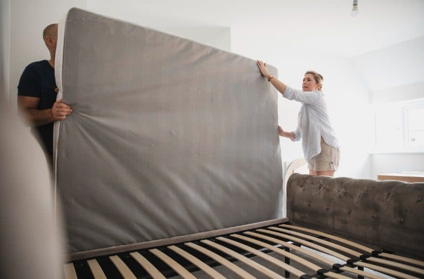 A couple setting up a bed after moving it to new house