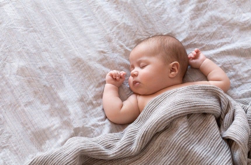 A cute baby sleeping on a bed
