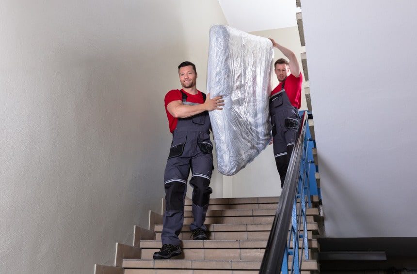 professional movers in uniform moving a mattress