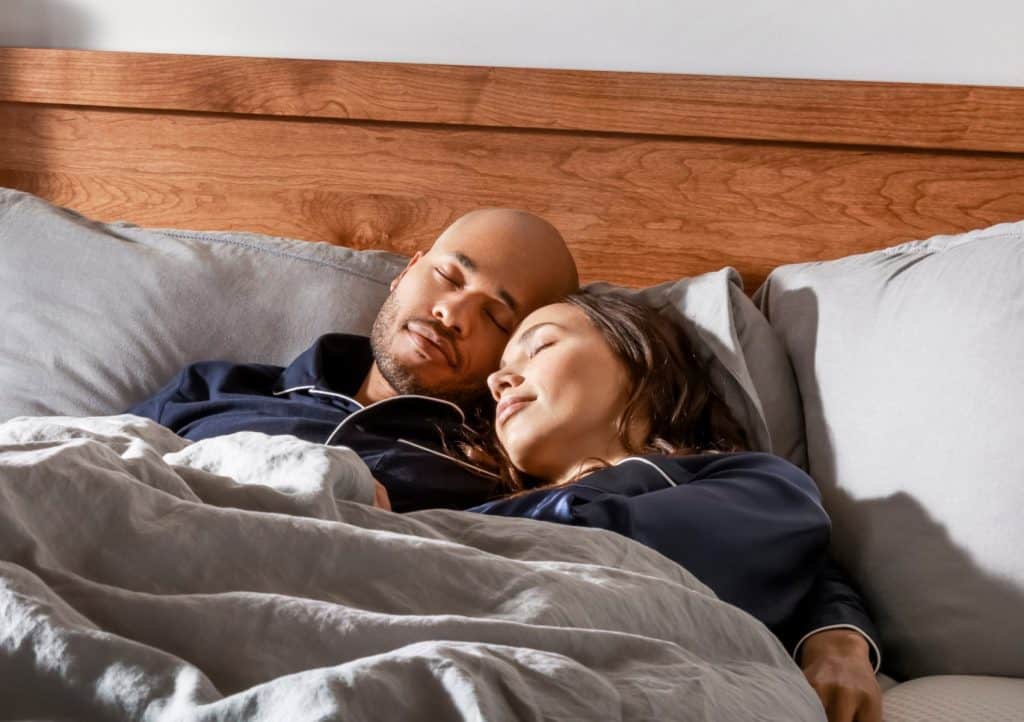 A Young couple sleeping on a Dreamcloud Mattress